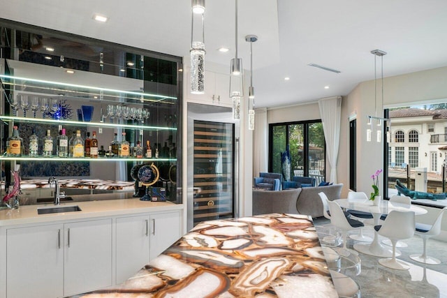 bar featuring hanging light fixtures, wine cooler, indoor wet bar, and a sink