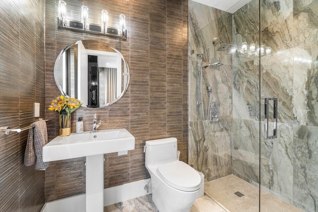 full bathroom with a marble finish shower, tile walls, and toilet