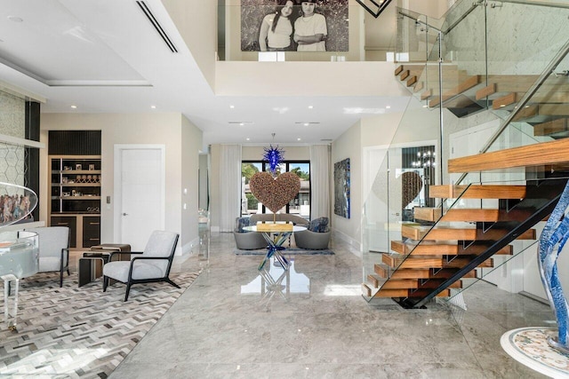 foyer entrance featuring a towering ceiling, baseboards, stairs, and visible vents