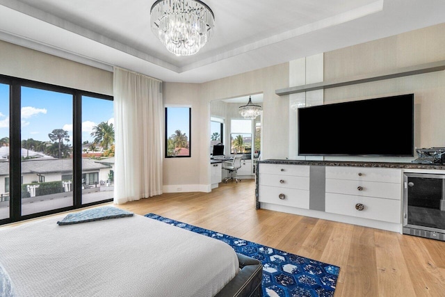 unfurnished bedroom featuring access to exterior, beverage cooler, a tray ceiling, and a notable chandelier