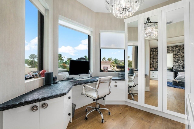 office with visible vents, a healthy amount of sunlight, light wood-style flooring, and a notable chandelier