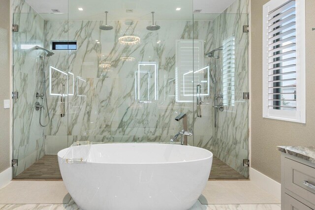 bathroom with marble finish floor, a freestanding bath, vanity, and a marble finish shower