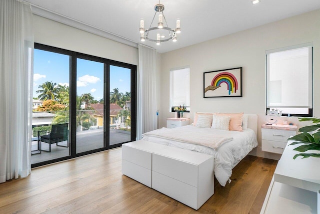 bedroom featuring light wood-type flooring, access to outside, and a notable chandelier