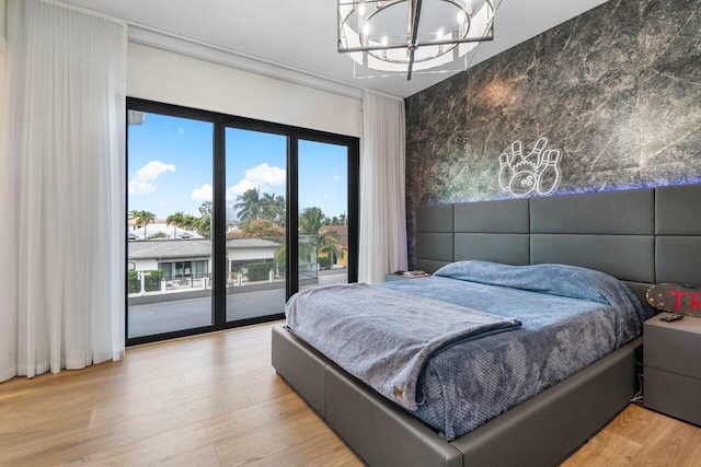 bedroom featuring light wood-type flooring, access to outside, and a chandelier