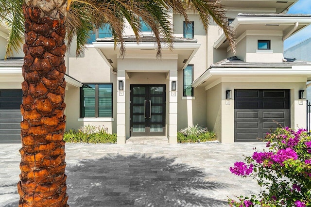 view of exterior entry featuring a garage, stucco siding, and french doors