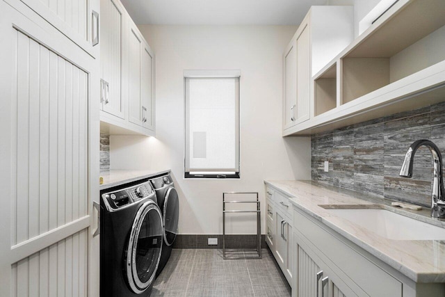 clothes washing area featuring a sink, cabinet space, tile patterned flooring, and washer and dryer