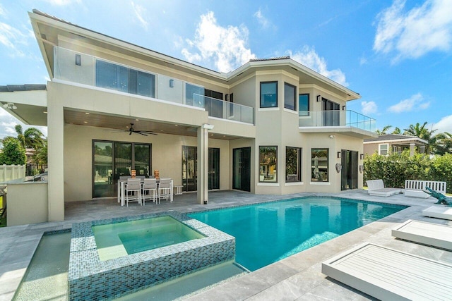 rear view of house featuring a ceiling fan, a balcony, and stucco siding