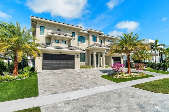 view of front of home with a garage, fence, decorative driveway, stucco siding, and a front yard