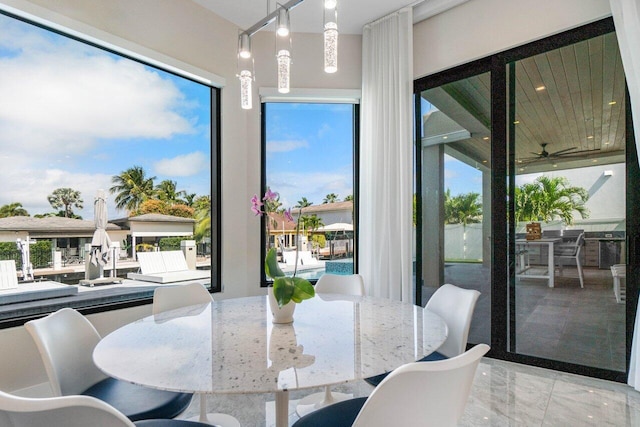 dining space featuring a ceiling fan and marble finish floor