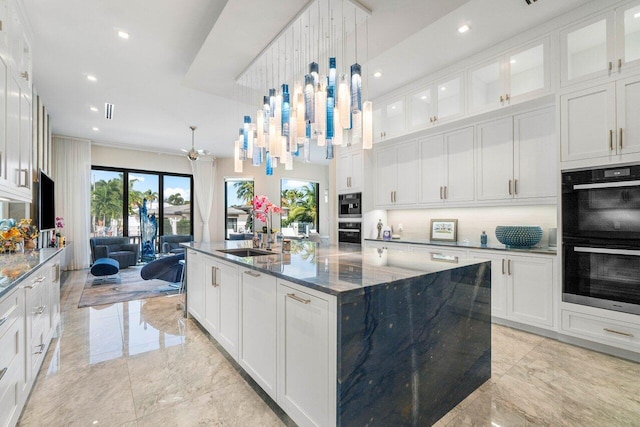 kitchen with white cabinetry, glass insert cabinets, a kitchen island with sink, and dobule oven black