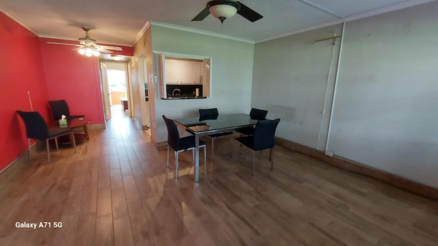 dining space with hardwood / wood-style flooring, ceiling fan, crown molding, and sink