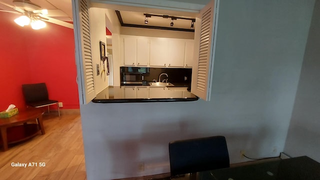 kitchen featuring white cabinetry, sink, ceiling fan, track lighting, and light wood-type flooring