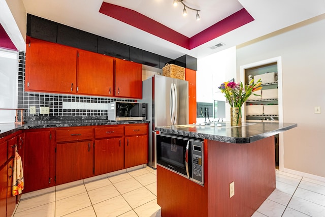 kitchen with light tile patterned floors, appliances with stainless steel finishes, kitchen peninsula, decorative backsplash, and a raised ceiling