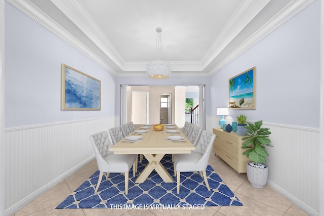 tiled dining space featuring ornamental molding, a raised ceiling, and decorative columns