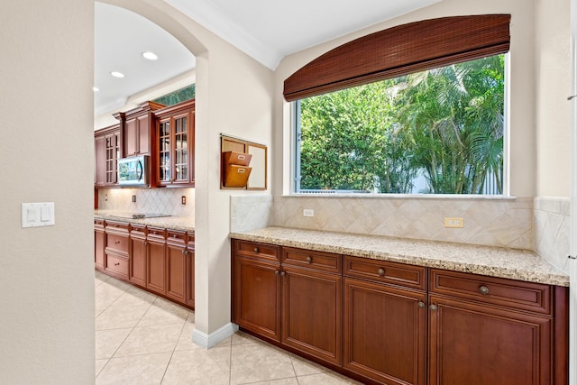 kitchen featuring decorative backsplash, crown molding, light stone counters, and light tile patterned floors