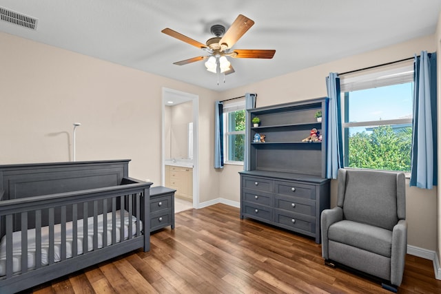 bedroom featuring ceiling fan, a crib, and dark hardwood / wood-style floors