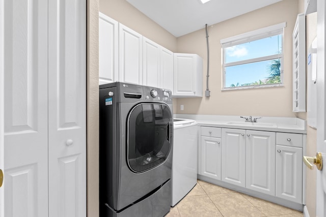 washroom featuring light tile patterned flooring, sink, washer and clothes dryer, and cabinets