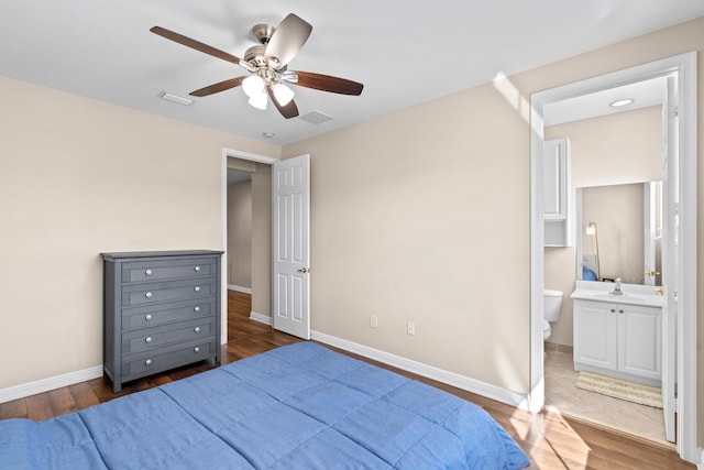 bedroom featuring sink, ceiling fan, dark hardwood / wood-style flooring, and ensuite bath