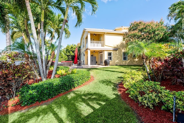 back of property with a yard, ceiling fan, a patio area, and a balcony