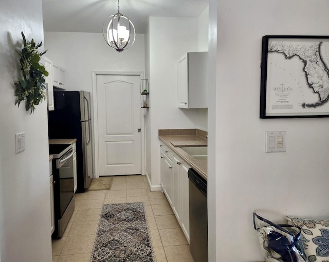 kitchen featuring light tile patterned flooring, stainless steel appliances, decorative light fixtures, and white cabinets