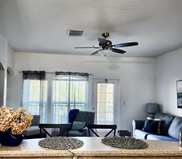 living room with ceiling fan and a textured ceiling