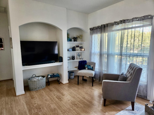 living area with hardwood / wood-style flooring and built in shelves