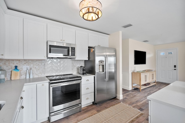 kitchen featuring visible vents, backsplash, wood finished floors, white cabinetry, and stainless steel appliances