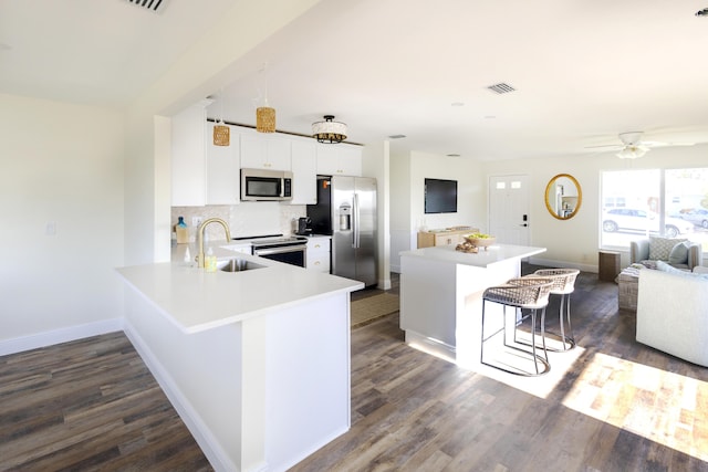 kitchen with appliances with stainless steel finishes, sink, a kitchen bar, decorative backsplash, and kitchen peninsula