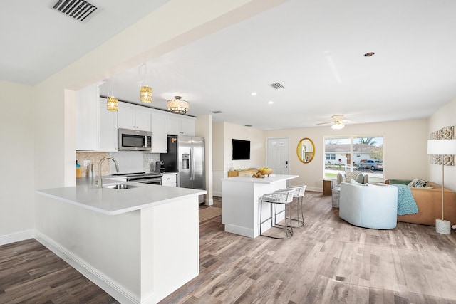 kitchen featuring visible vents, stainless steel appliances, a kitchen bar, open floor plan, and backsplash