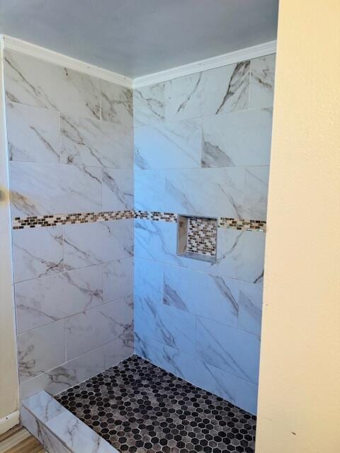 bathroom featuring ornamental molding and tiled shower