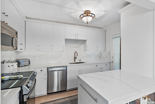 kitchen featuring sink, light hardwood / wood-style flooring, appliances with stainless steel finishes, backsplash, and white cabinets