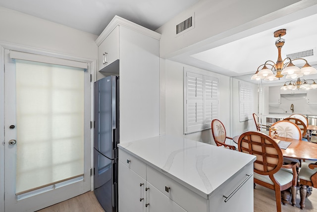 kitchen featuring fridge with ice dispenser, white cabinetry, light wood-type flooring, a notable chandelier, and pendant lighting