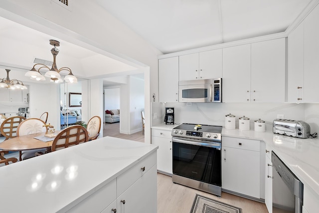 kitchen with stainless steel appliances, light hardwood / wood-style flooring, hanging light fixtures, and white cabinets