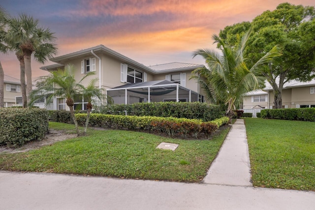 view of front of home with a lawn and a lanai