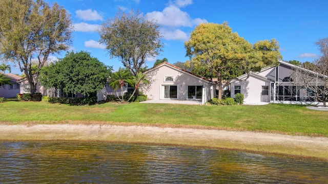 back of house featuring a lawn, a water view, and a lanai