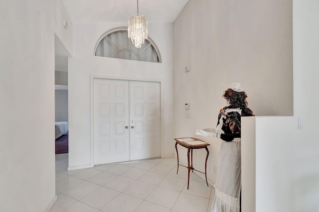 entrance foyer featuring light tile patterned flooring, an inviting chandelier, and a towering ceiling