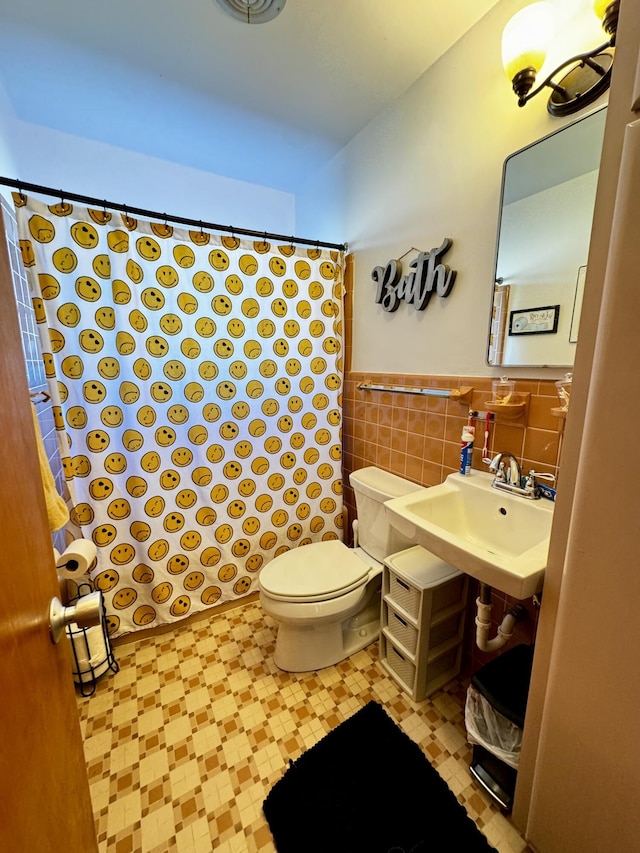 bathroom with toilet, sink, and tile walls