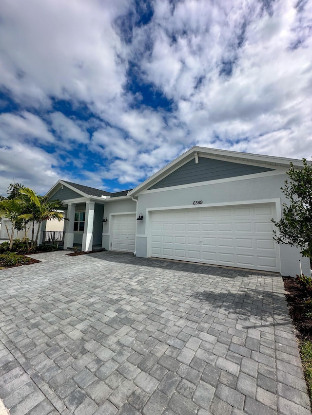 view of front of house featuring decorative driveway, an attached garage, and stucco siding