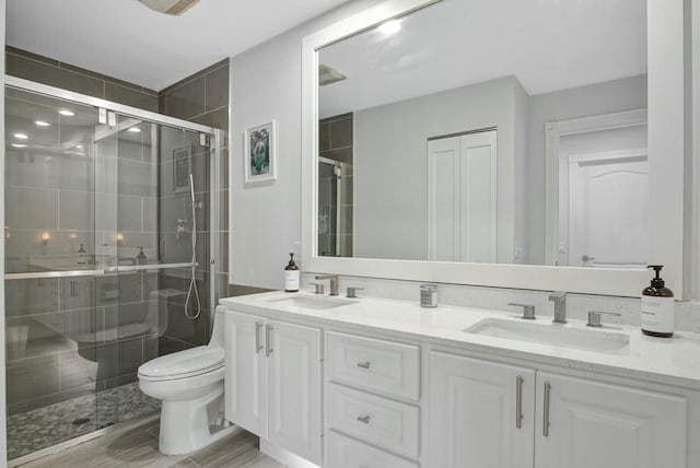 bathroom featuring a shower with door, vanity, and toilet