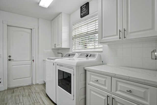 laundry room with cabinets, washing machine and dryer, and light wood-type flooring