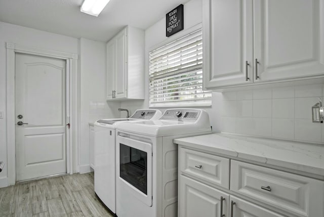 8376 SE Paurotis Ln, Hobe Sound, FL 33455 - laundry area featuring light wood finished floors, cabinet space, and washing machine and clothes dryer
