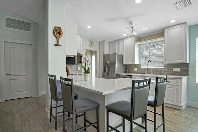 8376 SE Paurotis Ln, Hobe Sound, FL 33455 - kitchen with a kitchen bar, a peninsula, visible vents, and stainless steel appliances