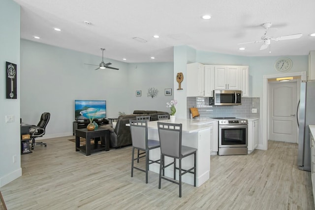 8376 SE Paurotis Ln, Hobe Sound, FL 33455 - kitchen with a breakfast bar area, a peninsula, stainless steel appliances, light countertops, and backsplash