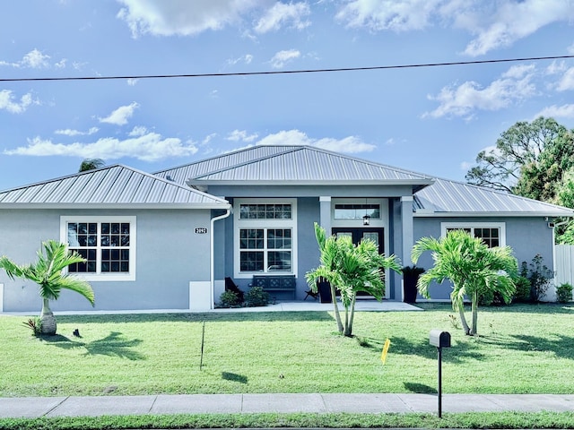 view of front of property with metal roof, a front lawn, and stucco siding