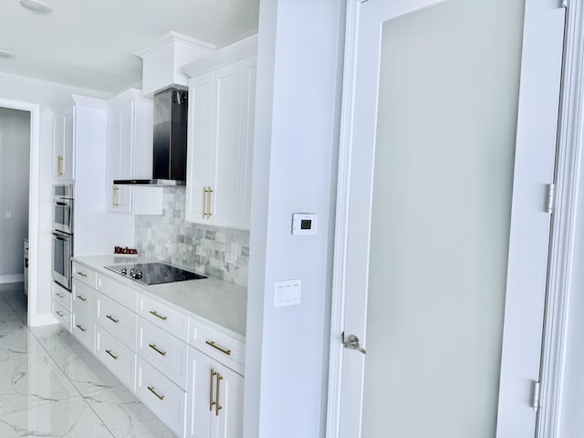 kitchen featuring marble finish floor, baseboards, wall chimney range hood, black electric cooktop, and backsplash