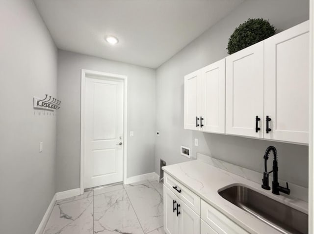 clothes washing area with cabinet space, electric dryer hookup, baseboards, and a sink