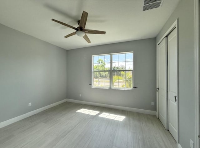 unfurnished bedroom with a ceiling fan, visible vents, light wood-type flooring, baseboards, and a closet
