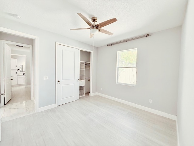 unfurnished bedroom featuring a textured ceiling, a closet, light wood-type flooring, and baseboards