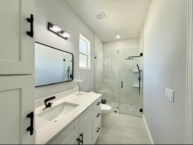 full bathroom with vanity, toilet, a marble finish shower, baseboards, and visible vents