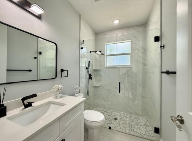 bathroom featuring toilet, a marble finish shower, and vanity